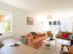 Ein Wohnzimmer mit einer Couch, einem Tisch und Blick auf Berge durch die Fenster.