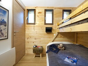 A compact room with a bunk bed, a small stool, a teddy bear, and a framed picture on the wall. - T2 Apartment, central and quiet - 4 guests (Les Deux Alpes)