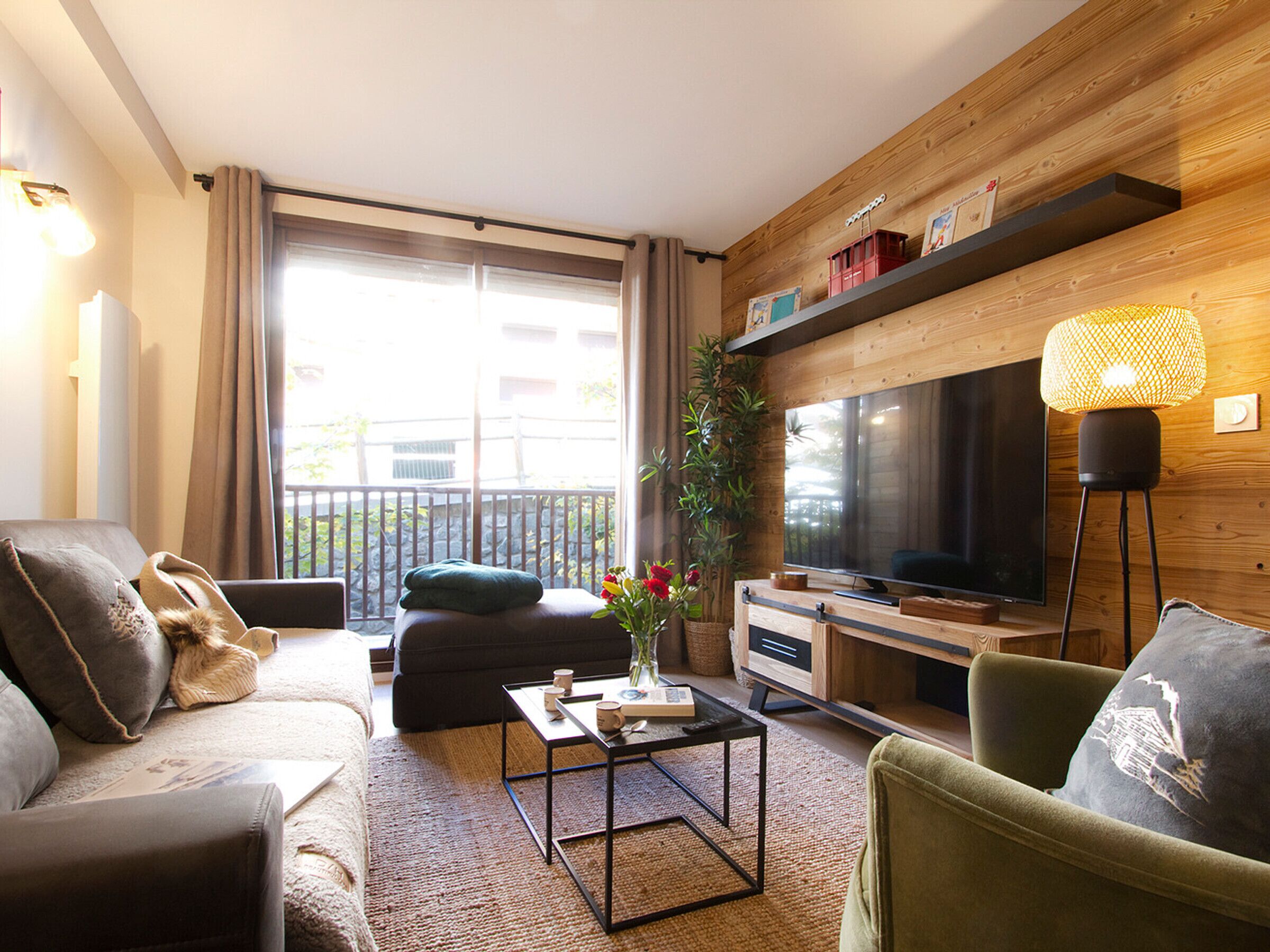 Ein modernes Wohnzimmer mit Sofa, Sessel, Couchtisch und Fernseher.