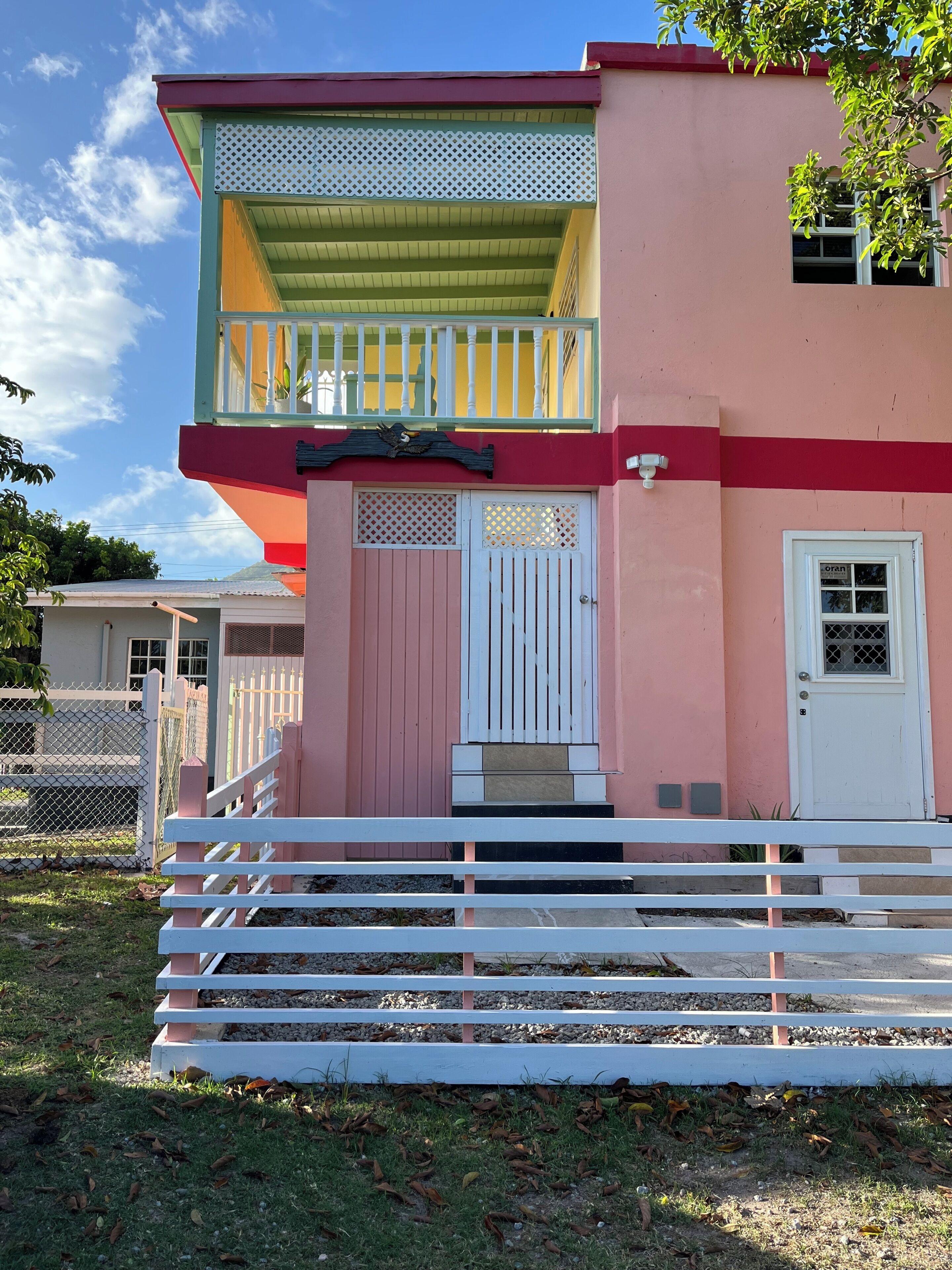 A two-story building with a balcony, a front door, and a small window.