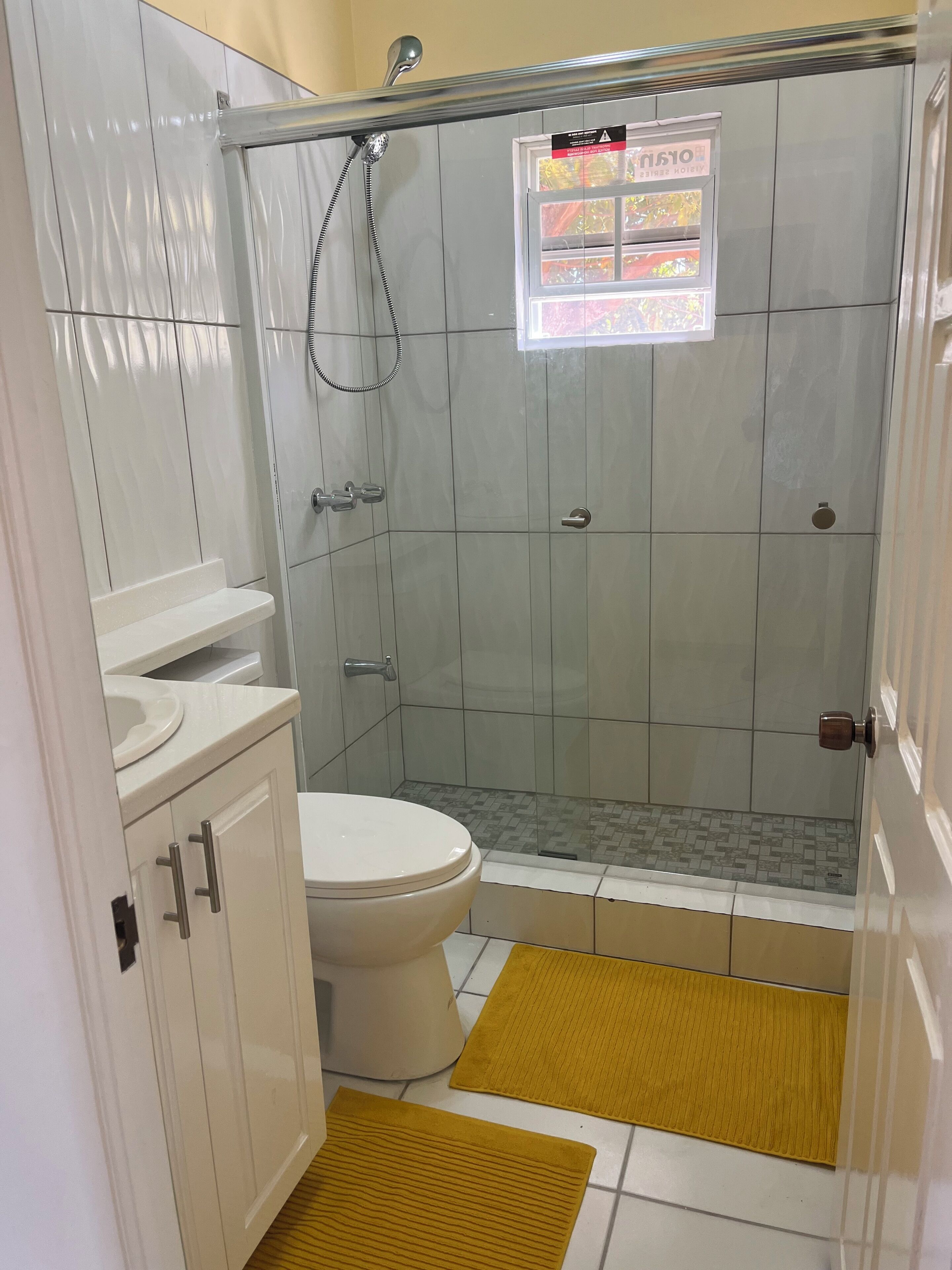 A bathroom with a toilet, a shower enclosure, and a sink.