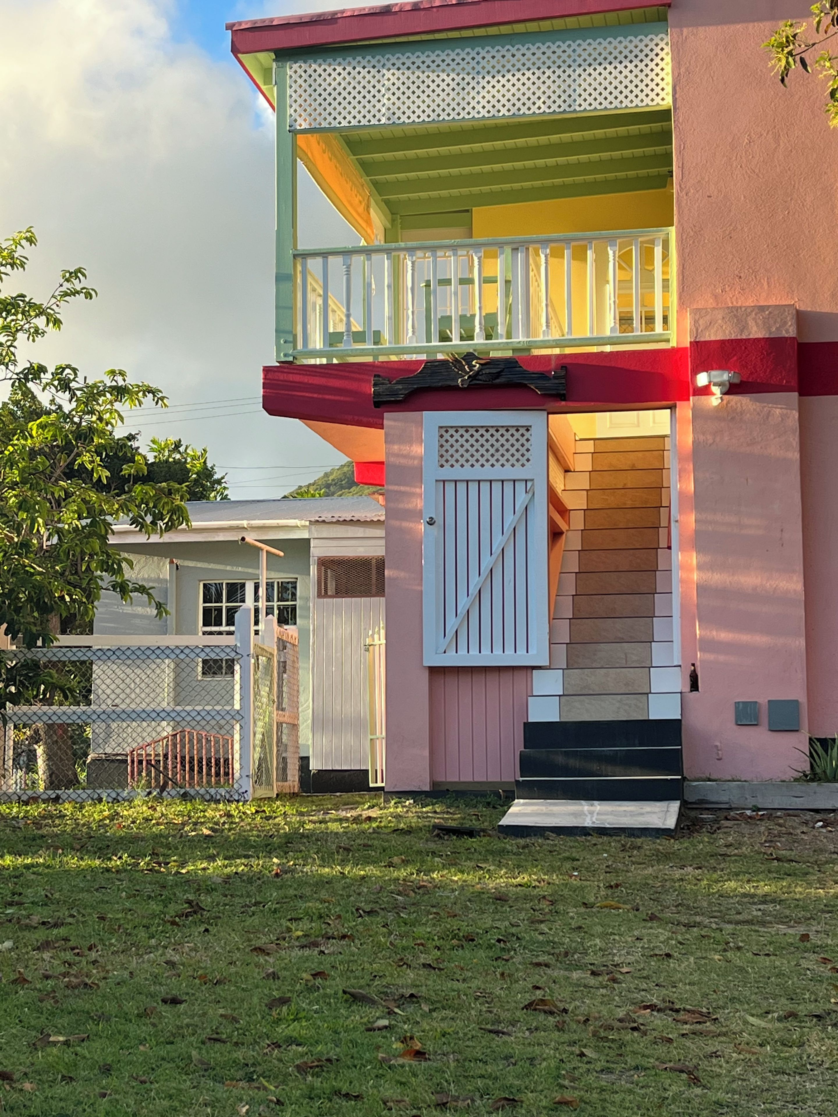 A two-story house with a balcony, a gated entrance, and a small front yard.