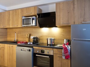 Eine moderne Küche mit Holzausstattung, einer eingebauten Mikrowelle, einem Edelstahlkühlschrank und einem Geschirrspüler.