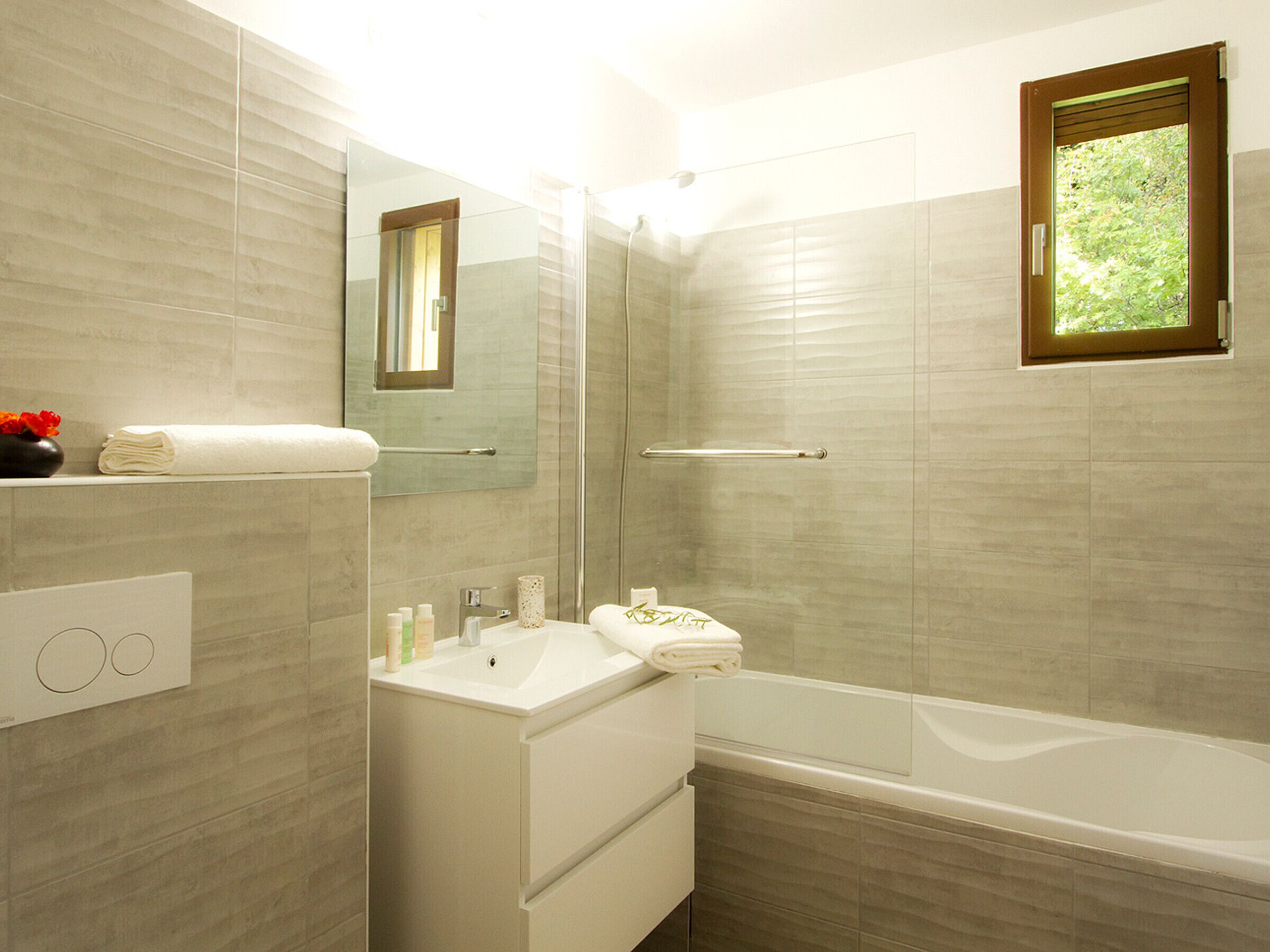Une salle de bain moderne avec une douche à parois de verre, un lavabo blanc et une baignoire.