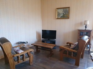 A living room with a television, wooden furniture, and a painting on the wall. - Charming house with a garden, ideal for families, close to shops and lakes (Brienne-le-Château)