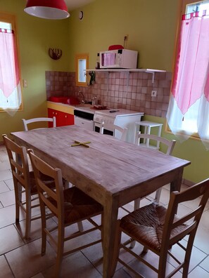 A kitchen with a dining table, chairs, and basic appliances. - Charming house with a garden, ideal for families, close to shops and lakes (Brienne-le-Château)