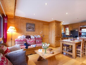 A cozy wooden interior with a sofa, a dining table, and a kitchen area. - Bright apartment at the foot of the slopes (Les Deux Alpes)