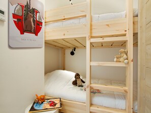 A bunk bed room with a poster on the wall, a small table with toys, and a teddy bear on the lower bunk. - Spacious ski-in/ski-out apartment - 6 guests (Huez)