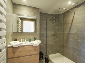 Une salle de bain moderne avec une douche, un lavabo avec un miroir et des toilettes.