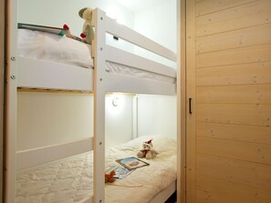 Een stapelbed met een witte matras, een teddybeer en een boek op het onderste bed.