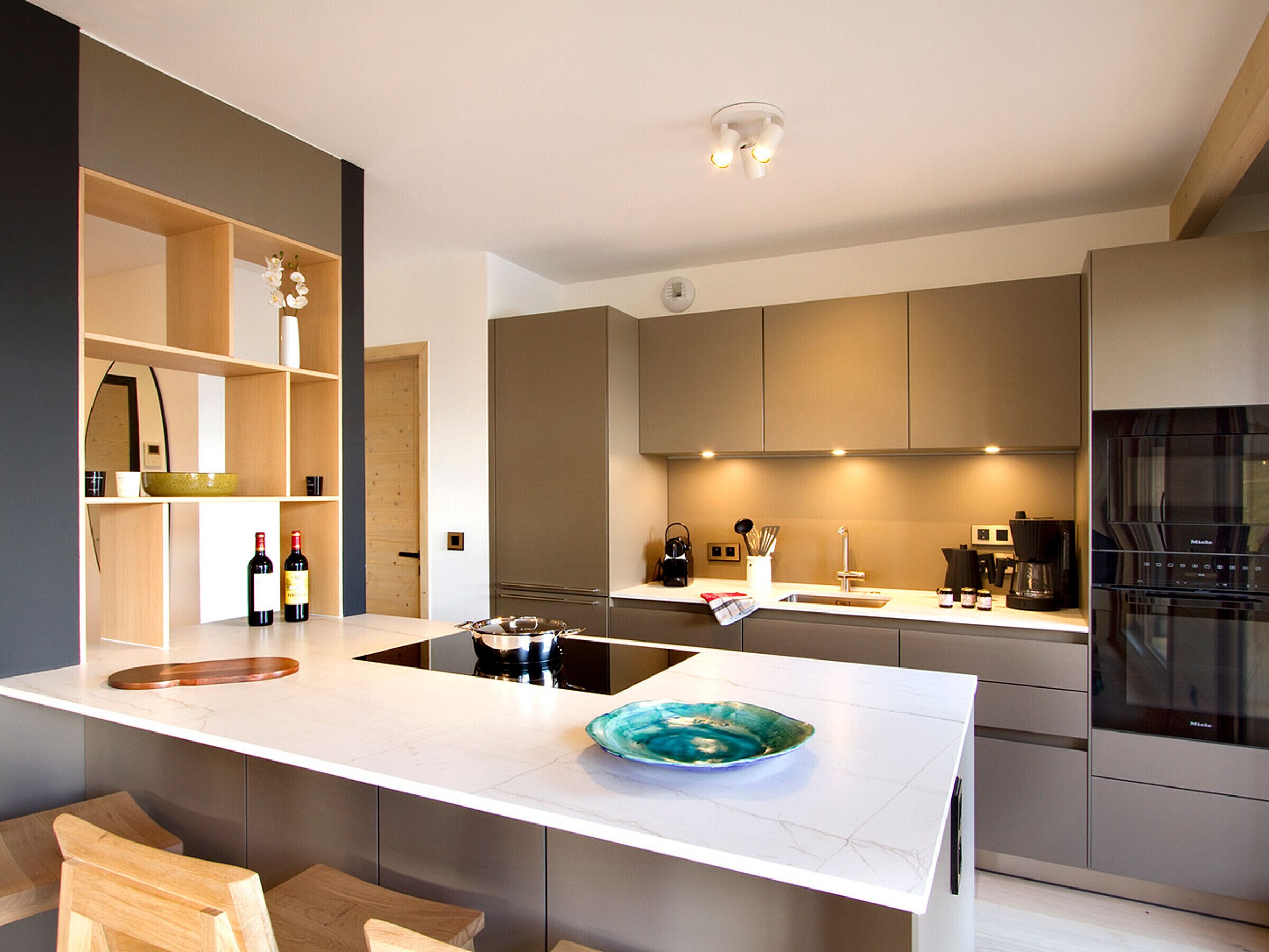 A modern kitchen with a central island, built-in appliances, and wooden cabinetry.