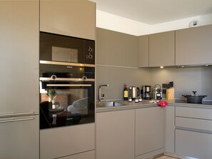 Une cuisine moderne équipée d’un four encastré, d’une machine à café et d’une casserole posée sur le plan de travail.