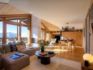 A spacious living area with a large window, a cozy seating area, and a dining space. - Bright top-floor apartment, slope view - 6 guests (Huez)