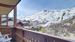 Un balcon offrant une vue sur des montagnes enneigées et un village situé en contrebas.