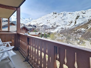 Ein Balkon mit Blick auf schneebedeckte Berge und ein Dorf darunter.