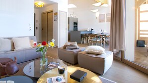 A modern living room with a sofa, a coffee table, and a dining area with chairs and a table. - Spacious apartment, slope view - 10 guests (Huez)