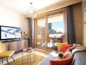 Een moderne woonkamer met een televisie, bank en een kleine tafel met een bloevas.