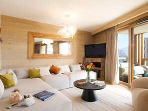 Ein modernes Wohnzimmer mit einer großen Couch, einem Couchtisch und einem flachbildfernseher an der Wand.