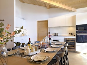 A modern kitchen with white cabinetry, a dining table set for four with plates, glasses, and a vase of flowers. - Magnificent top-floor apartment - 8 guests (Huez)