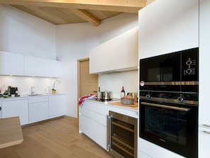 A modern kitchen with white cabinetry, a built-in oven, and a coffee machine. - Magnificent top-floor apartment - 8 guests (Huez)