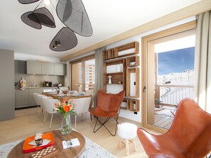 A modern interior with a dining area, kitchen, and a balcony with a view. - Luxury apartment, station view - 6 guests (Huez)