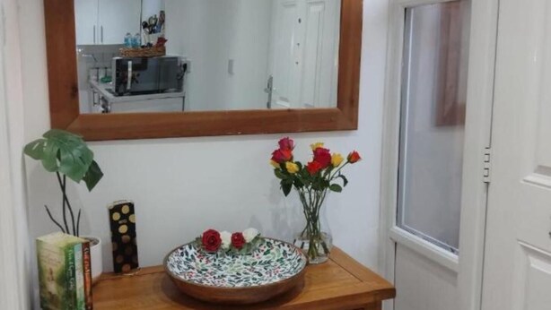 A wooden vanity with a mirror above it, a vase with flowers, and a potted plant beside the mirror.