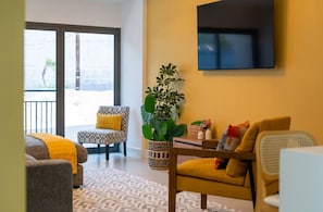A living room with a sofa, armchair, and a potted plant.