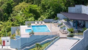 Un hôtel moderne doté d’une piscine sur le toit, d’un espace extérieur aménagé et d’un escalier menant à une zone couverte.