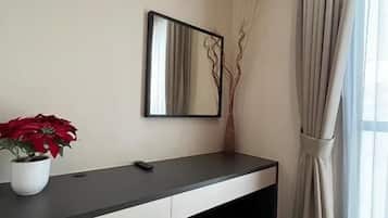 Una habitación moderna con escritorio, espejo, planta en maceta y ventana con cortinas.