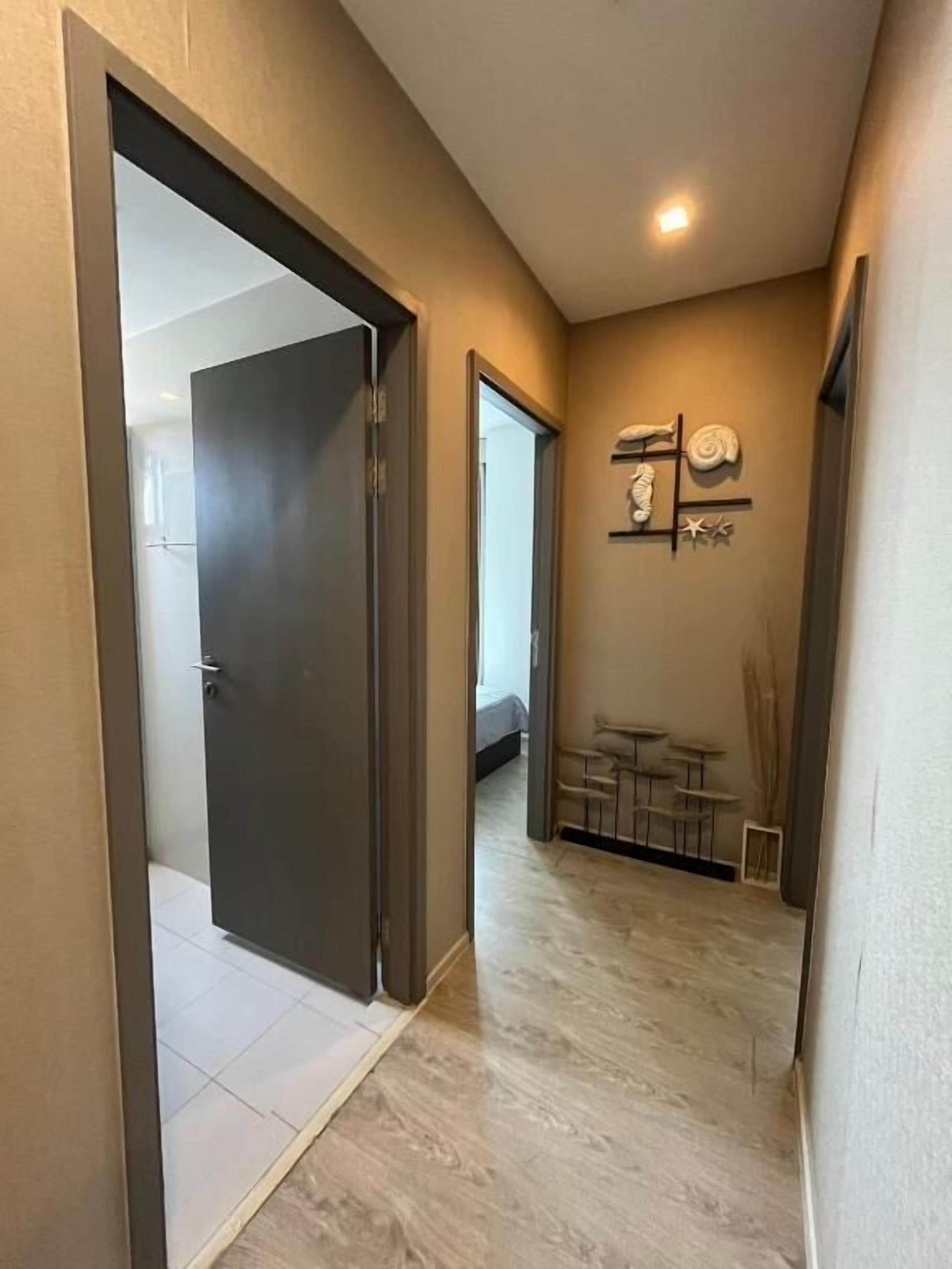 Un couloir avec une porte donnant sur une chambre, une petite table avec des chaises et un porte-serviettes fixé au mur.