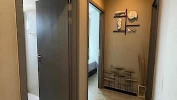 Un couloir avec une porte donnant sur une chambre, une petite table avec des chaises et un porte-serviettes fixé au mur.
