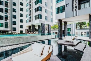 Un hôtel moderne doté d’un espace piscine sur le toit, comprenant des chaises longues et une piscine.