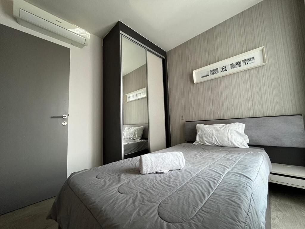 Une chambre d’hôtel comprenant un lit, une table de chevet, un miroir et une étagère murale décorée de tableaux.