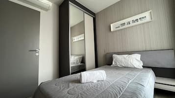 Une chambre d’hôtel comprenant un lit, une table de chevet, un miroir et une étagère murale décorée de tableaux.