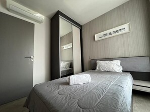 Une chambre d’hôtel comprenant un lit, une table de chevet, un miroir et une étagère murale décorée de tableaux.