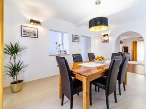A dining area with a wooden table, black chairs, a fruit bowl, and wall-mounted lights. - Spacious Mediterranean 3-bedroom Apartment in Sutivan (Sutivan)