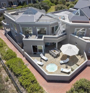 A modern multi-story house with a rooftop deck, outdoor seating, and a swimming pool. - PINGU Beachhouse | Beachfront Villa with Hot Tub, Ocean Views & Beach Access (Cape Town)