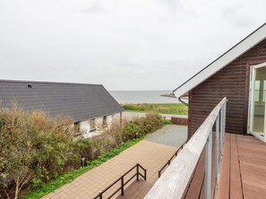 A coastal building with a balcony overlooking a paved walkway and a grassy area. - 4 Star Holiday Home in Vestervig (Vestervig)