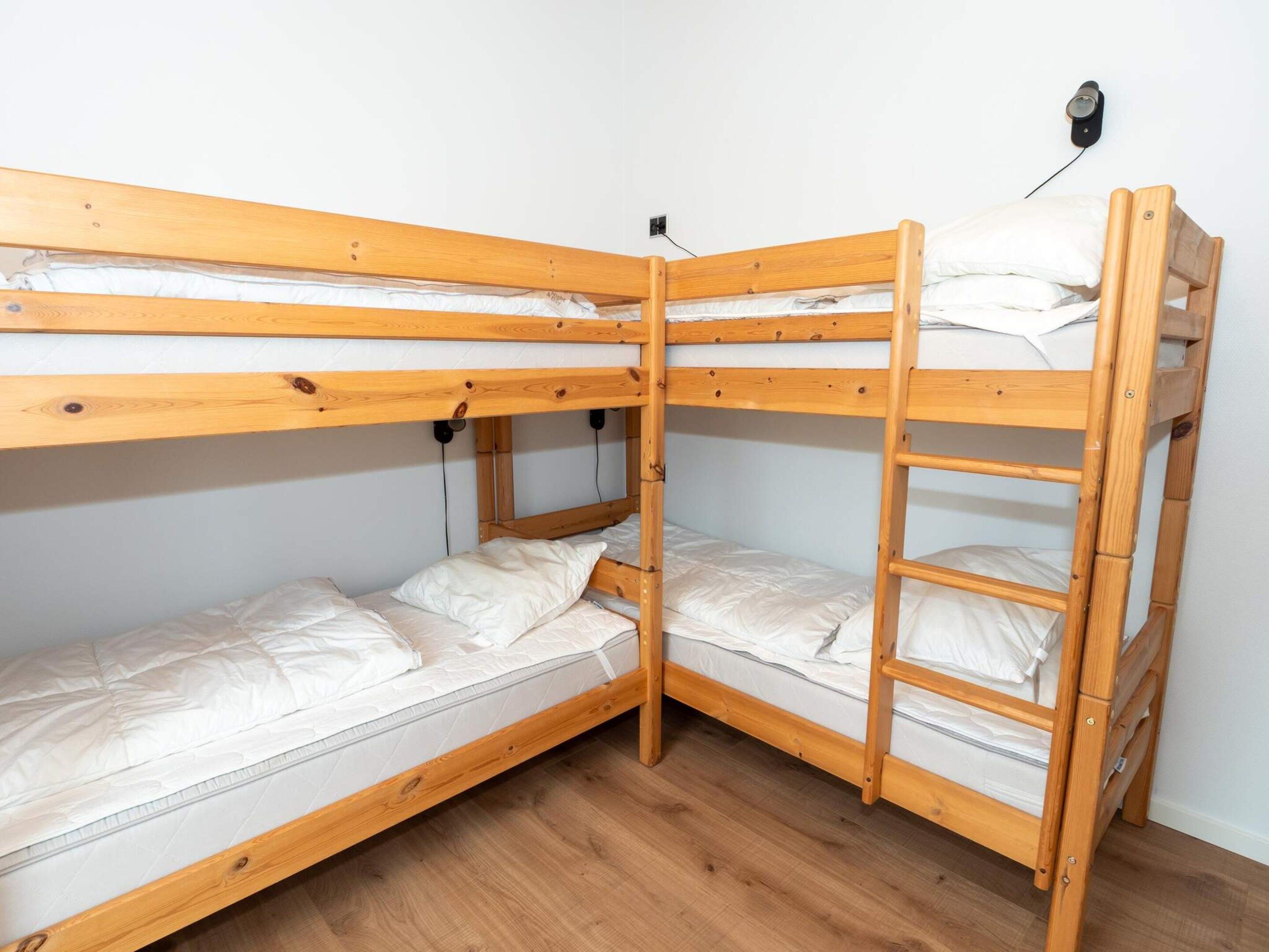 A bunk bed with a wooden frame and white bedding.