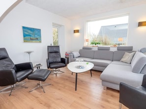 A modern living room with a grey sofa, black leather chairs, a white coffee table, and a painting of a sailboat. - 4 Star Holiday Home in Vestervig (Vestervig)