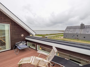 A modern outdoor deck with a panoramic view of a body of water and a distant building. - 4 Star Holiday Home in Vestervig (Vestervig)