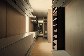 A narrow hallway with built-in shelving units on both sides, a bench in the center, and a view into a room at the end. - Crown Ridge Estate - Exclusive Hollywood Hills Retreat | Resort-Style Living (Hollywood Hills)