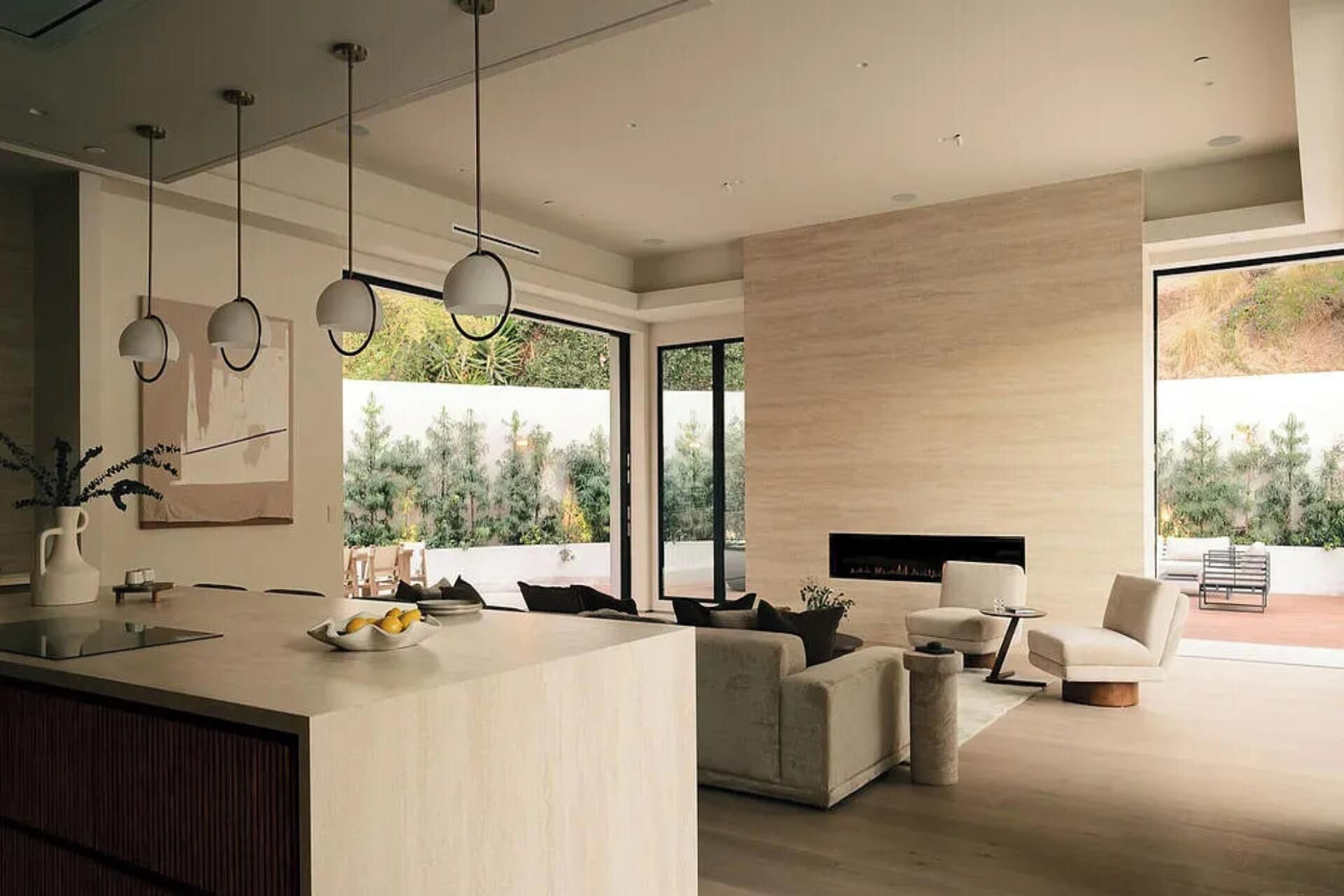 A modern kitchen with a central island, dining area with a sofa and chairs, and a fireplace.