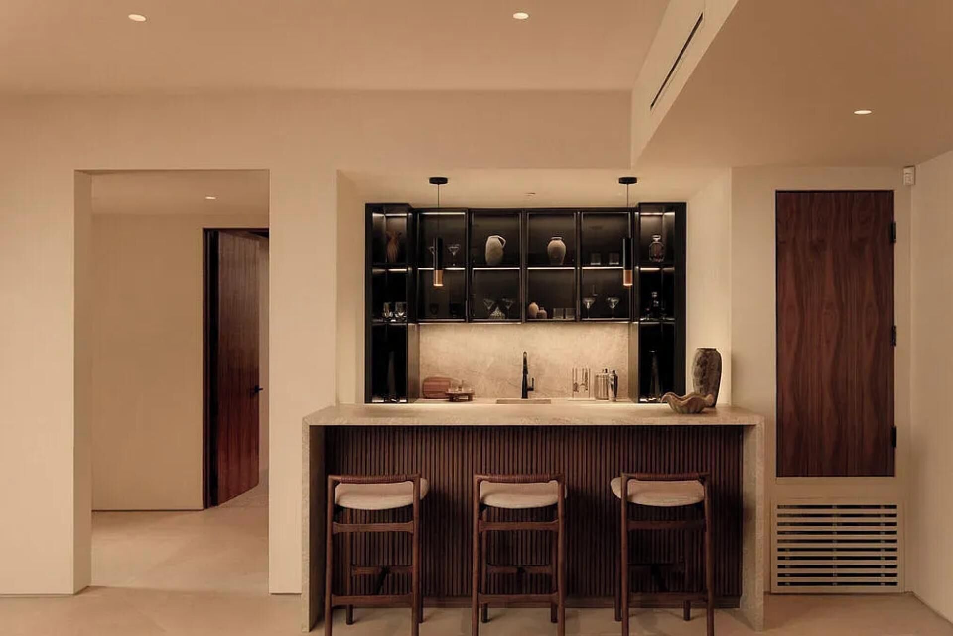 A modern kitchen with a central island, bar stools, and a built-in wine rack.