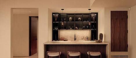 A modern kitchen with a central island, bar stools, and a built-in wine rack.