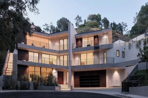 A modern multi-story building with a central atrium, large windows, and a garage. - Crown Ridge Estate - Exclusive Hollywood Hills Retreat | Resort-Style Living (Hollywood Hills)