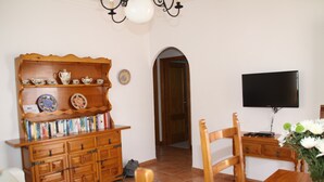 Un salon avec un meuble en bois, un téléviseur et une table à manger.
