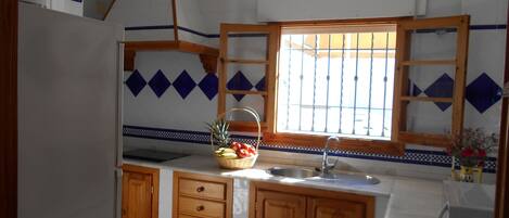 Una cocina con armarios de madera, un lavamanos y una ventana con rejas.