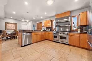 A modern kitchen with wooden cabinets, stainless steel appliances, and a dining area with a table and chairs. - SEASIDE SOIREE ~ NEW LISTING! Key Haven 4 BR/3 Ba Waterfront Home! (Key West)
