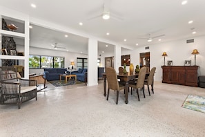 A spacious living area with a blue sofa, dining table, and chairs, a kitchen in the background, and a ceiling fan. - SEASIDE SOIREE ~ NEW LISTING! Key Haven 4 BR/3 Ba Waterfront Home! (Key West)
